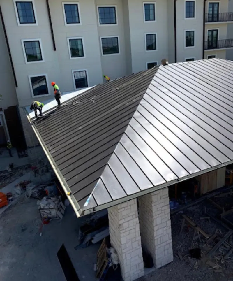 Crew installing standing seam metal roof panels on a commercial project in College Park